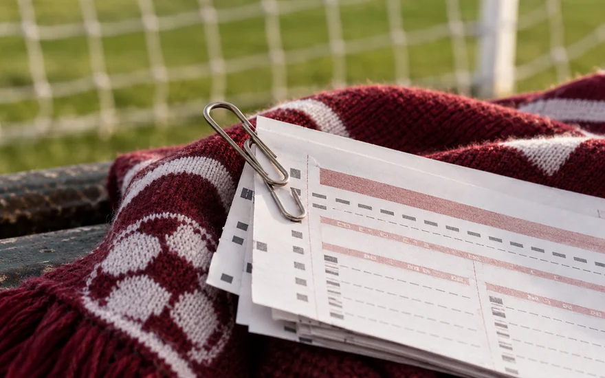 Linked clips holding separate paper betting-slip sections together