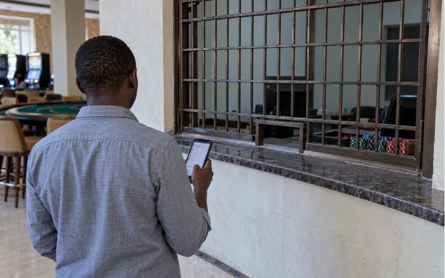 An adult checks a blurred wallet screen outside a closed casino cashier window