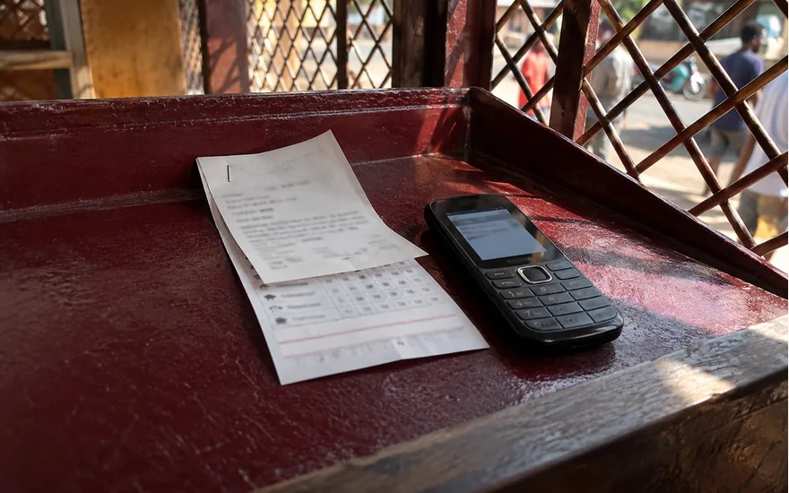 A mobile money receipt and football slip beside a payment confirmation phone